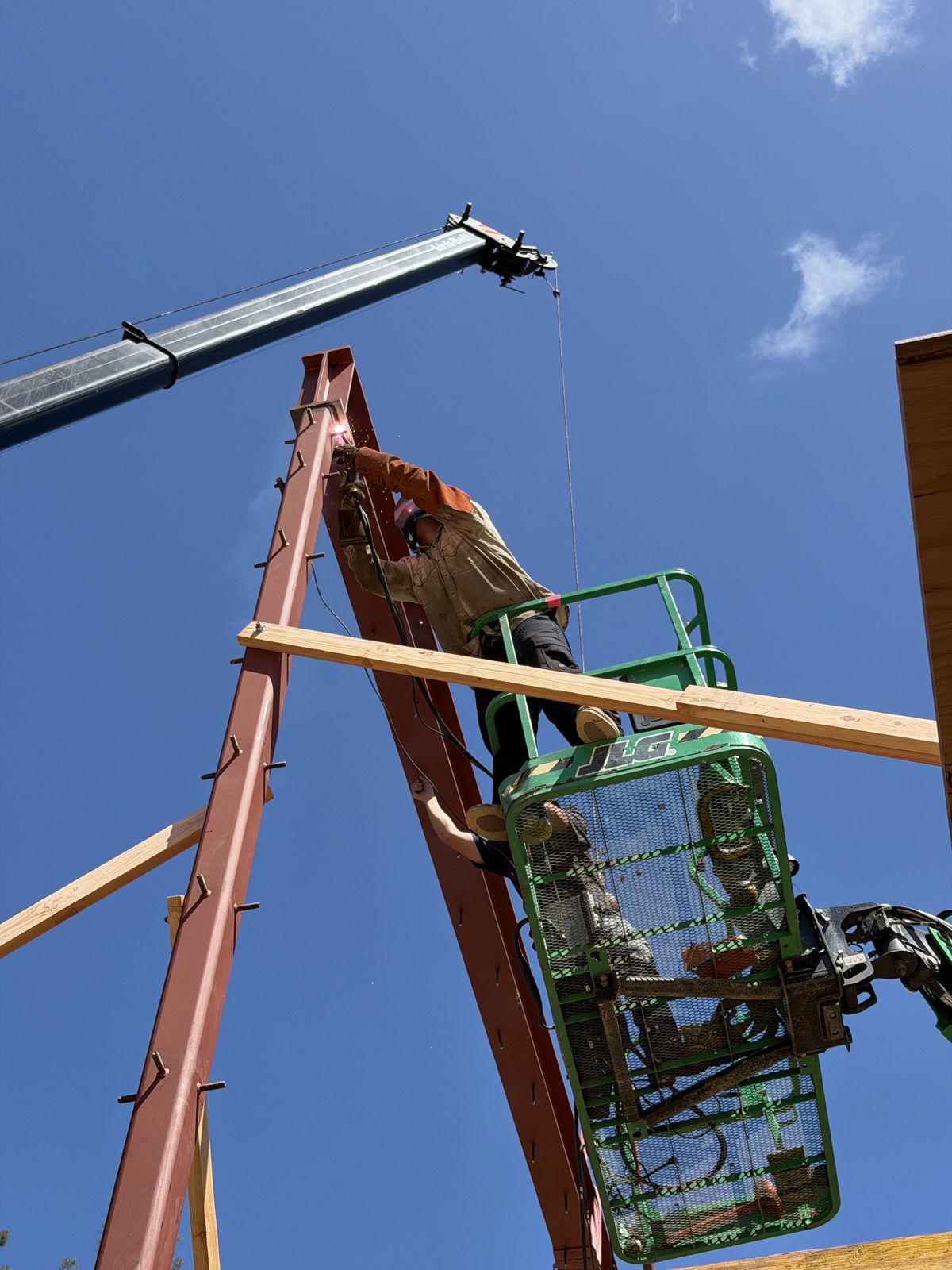 Steel column being set with a crane and a man lift